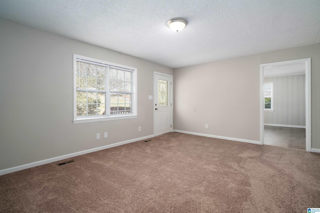 unfurnished room featuring carpet, visible vents, and a wealth of natural light