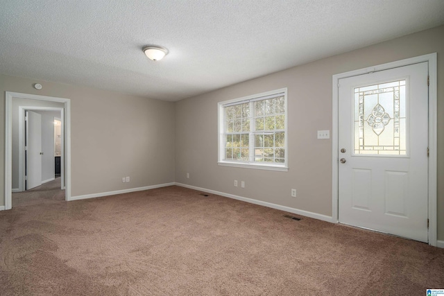 entrance foyer featuring carpet floors, visible vents, baseboards, and a textured ceiling