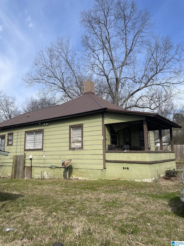 view of home's exterior with crawl space, metal roof, a chimney, and a lawn