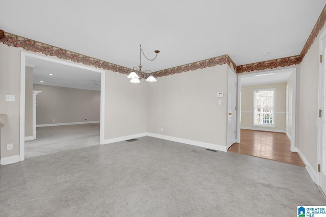 spare room with an inviting chandelier, visible vents, and baseboards