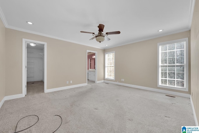 unfurnished bedroom with carpet floors, crown molding, visible vents, a spacious closet, and baseboards