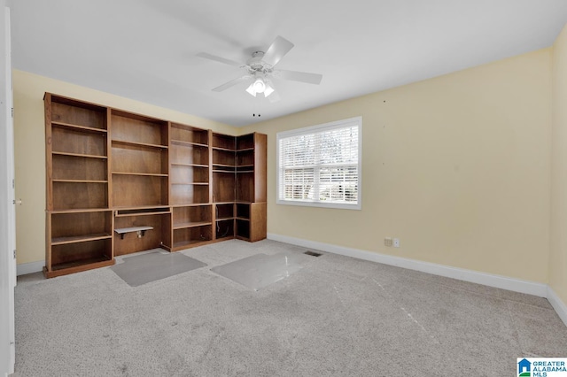 carpeted empty room with visible vents, ceiling fan, and baseboards