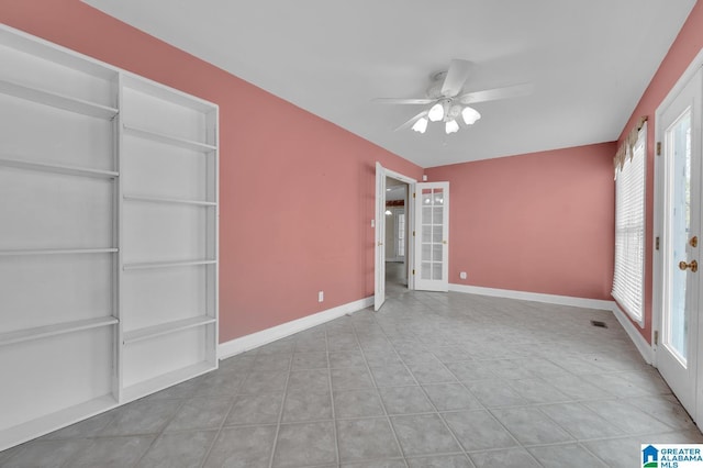 empty room with tile patterned floors, baseboards, a ceiling fan, and french doors