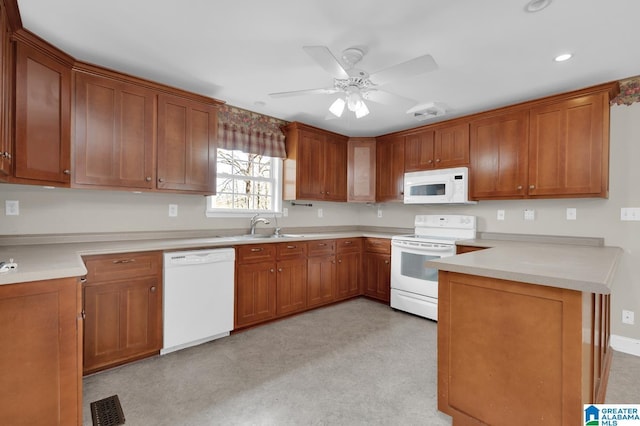 kitchen featuring white appliances, visible vents, brown cabinets, and a sink