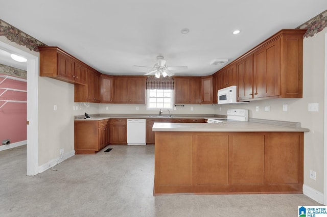 kitchen with a peninsula, white appliances, brown cabinetry, and a sink