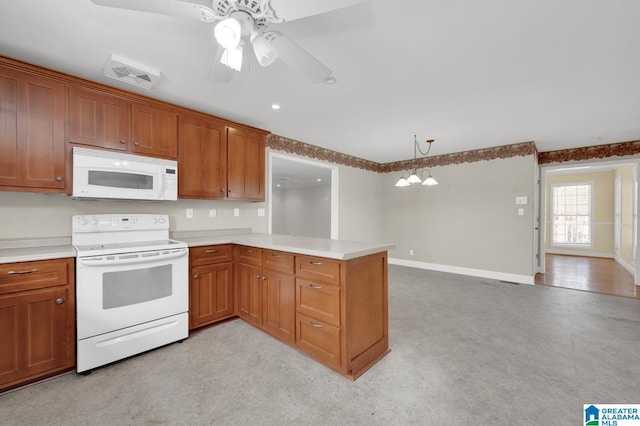 kitchen featuring brown cabinets, white appliances, light countertops, and a peninsula