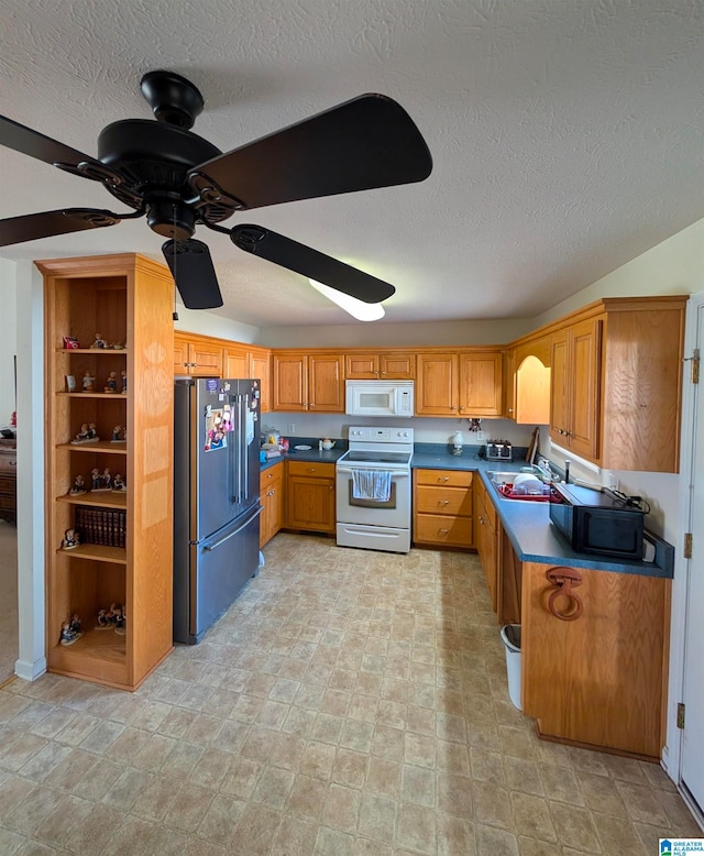 kitchen featuring a sink, brown cabinets, white appliances, dark countertops, and ceiling fan