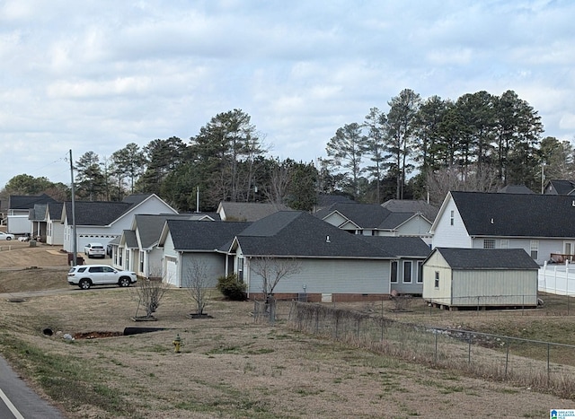 view of front of property featuring a residential view, fence, and an outdoor structure