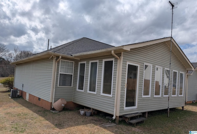 view of side of property with central air condition unit and roof with shingles