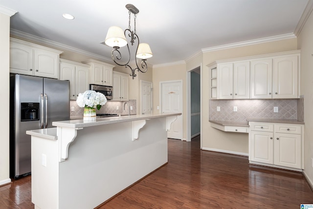 kitchen with white cabinets, appliances with stainless steel finishes, ornamental molding, dark wood-type flooring, and pendant lighting