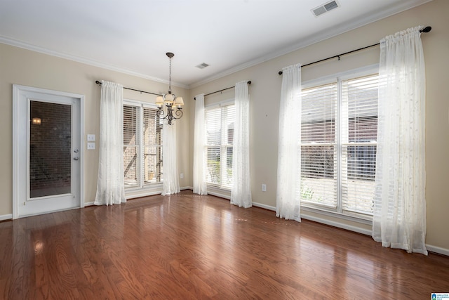 unfurnished dining area with ornamental molding, a chandelier, visible vents, and wood finished floors