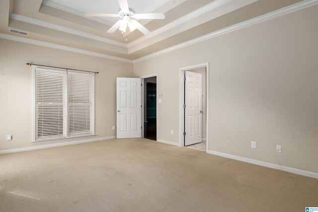 unfurnished bedroom with light carpet, a tray ceiling, visible vents, and baseboards