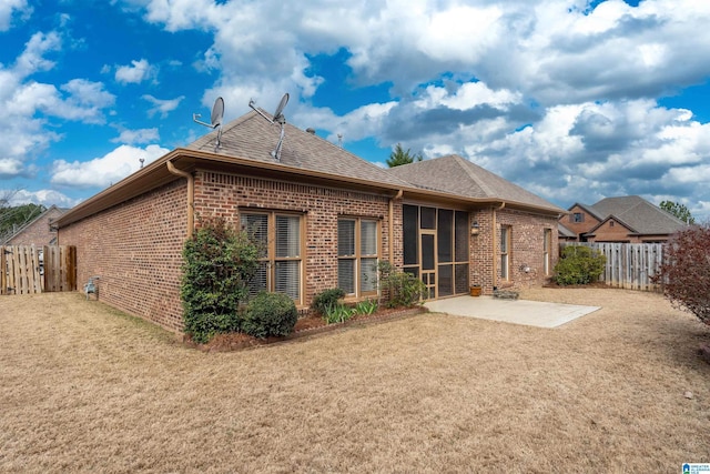 back of property featuring brick siding, a yard, roof with shingles, a patio area, and a fenced backyard