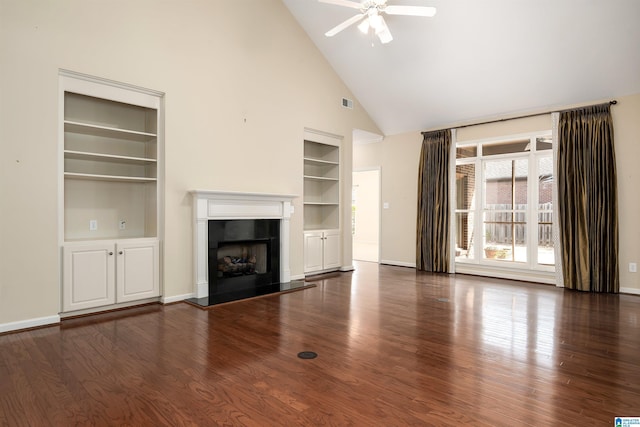 unfurnished living room featuring built in shelves, a premium fireplace, wood finished floors, and baseboards