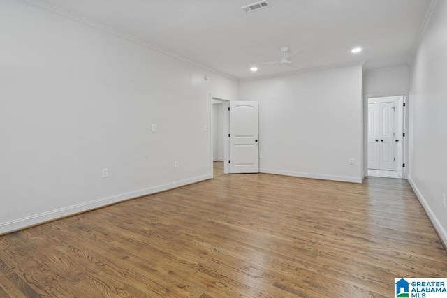 spare room featuring ceiling fan, visible vents, baseboards, ornamental molding, and light wood-type flooring