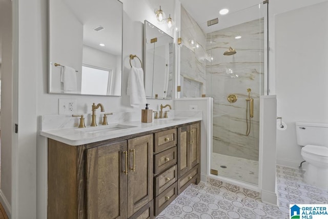 bathroom featuring toilet, double vanity, a marble finish shower, and a sink