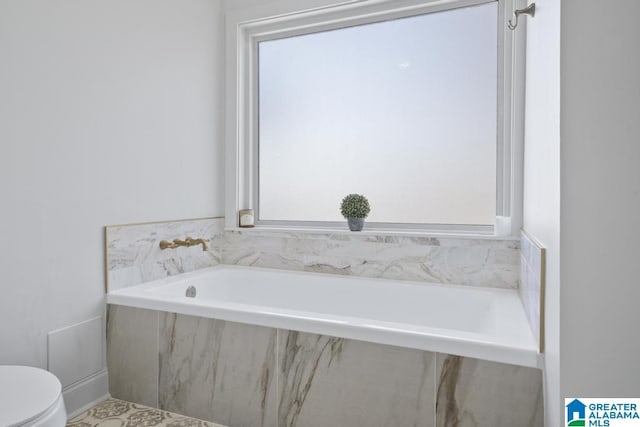 bathroom with a garden tub and toilet