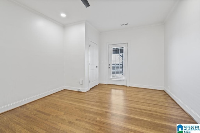 empty room with ornamental molding, light wood-style flooring, and baseboards