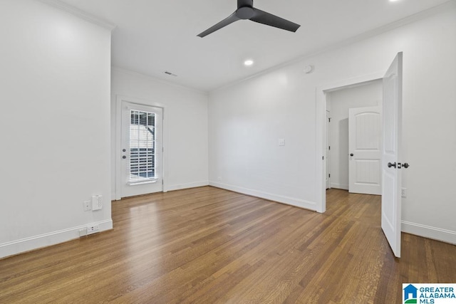 empty room with ceiling fan, wood finished floors, visible vents, baseboards, and crown molding