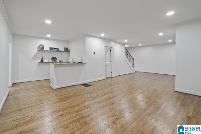 interior space featuring recessed lighting, wet bar, light wood-type flooring, baseboards, and stairs