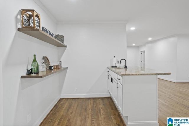 kitchen with open shelves, a peninsula, wood finished floors, and light stone countertops