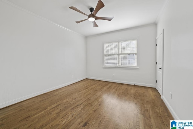 spare room with baseboards, wood finished floors, and crown molding