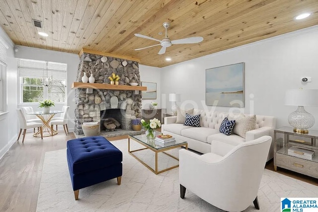 living area featuring visible vents, ornamental molding, wood ceiling, a stone fireplace, and wood finished floors