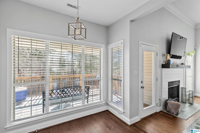 dining space with dark wood-style floors, a fireplace, crown molding, visible vents, and baseboards