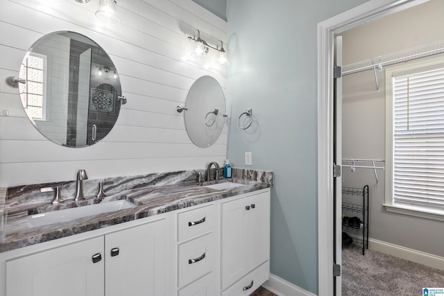 bathroom with a spacious closet, a sink, and baseboards