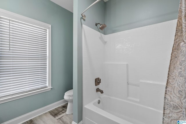 bathroom with baseboards, shower / tub combo with curtain, toilet, and wood finished floors