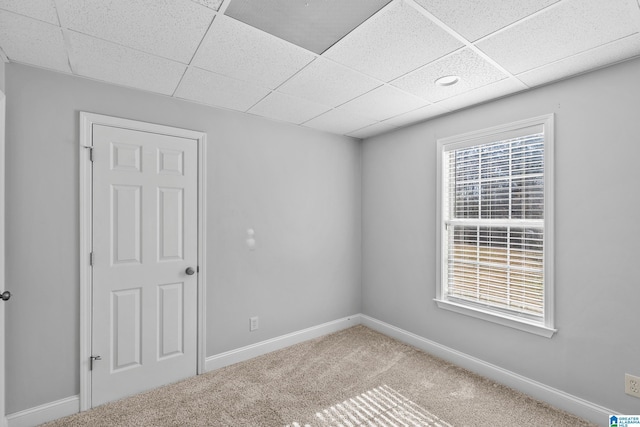 carpeted spare room with a paneled ceiling and baseboards