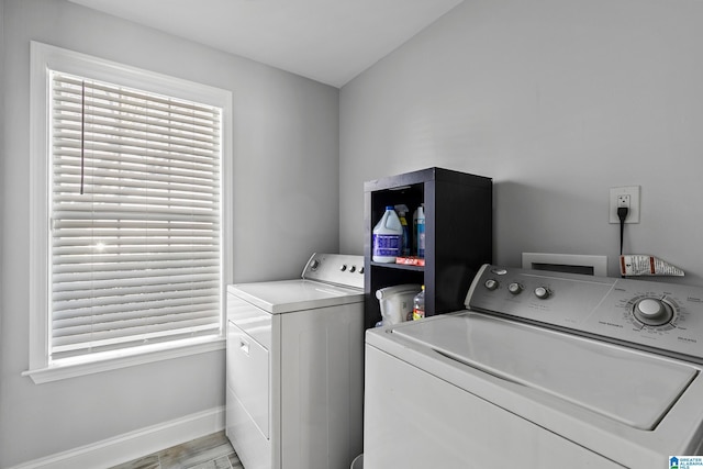 clothes washing area with laundry area, light wood-style flooring, baseboards, and washing machine and clothes dryer