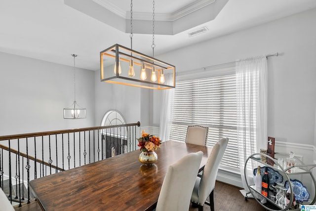 dining room featuring visible vents, dark wood-style floors, a tray ceiling, crown molding, and a notable chandelier