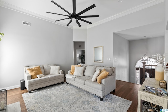 living room with ceiling fan with notable chandelier, ornamental molding, wood finished floors, and visible vents