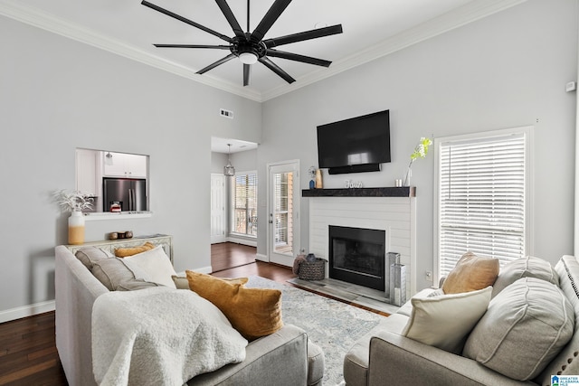 living room with baseboards, a ceiling fan, dark wood-style floors, a fireplace with flush hearth, and crown molding