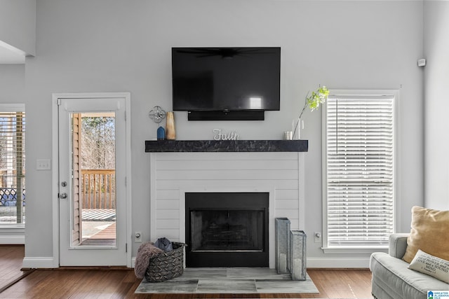 living area featuring a fireplace, baseboards, and wood finished floors