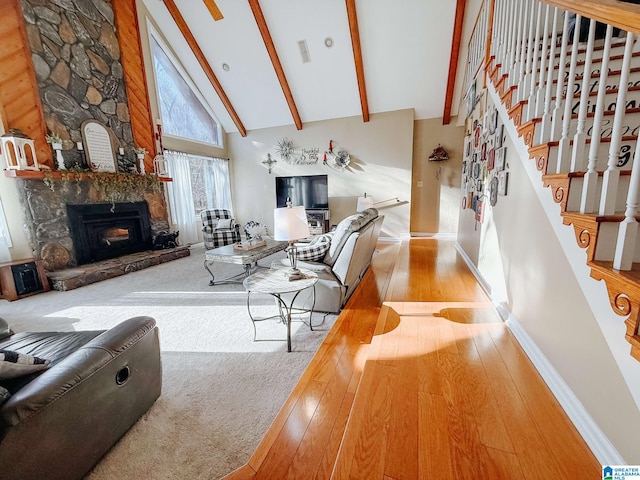 living area with beam ceiling, a fireplace, wood-type flooring, high vaulted ceiling, and stairs