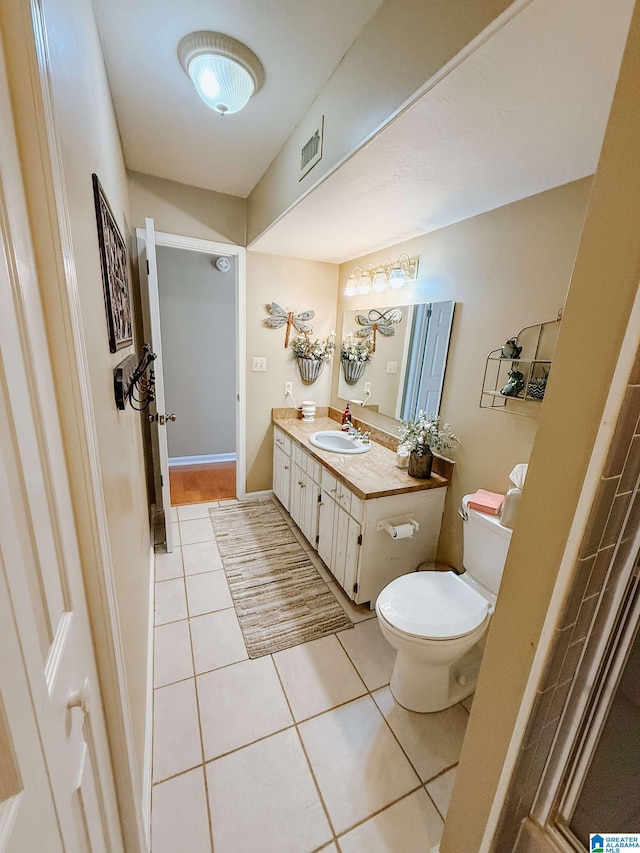 bathroom with tile patterned flooring, toilet, vanity, visible vents, and baseboards