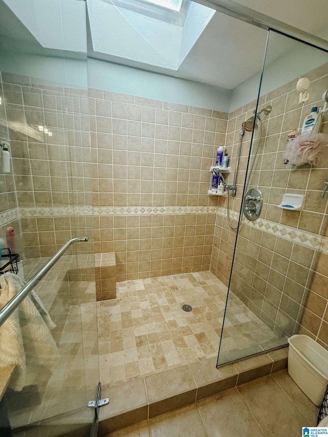 full bath featuring toilet, a skylight, tile patterned flooring, and a stall shower