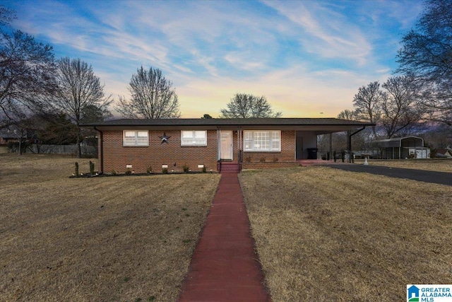 single story home with brick siding, a carport, and a yard