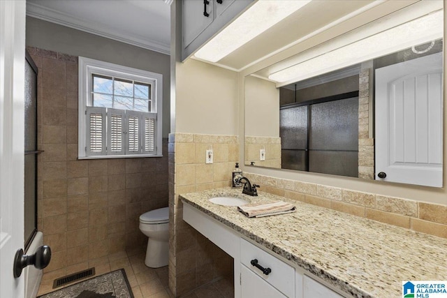 bathroom featuring crown molding, tile walls, visible vents, toilet, and tile patterned floors