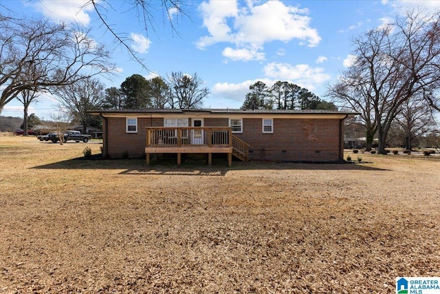 back of property with a deck, a yard, brick siding, and crawl space