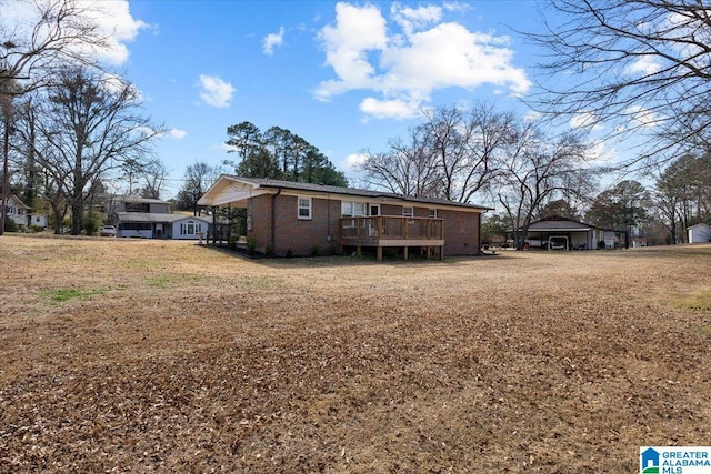 rear view of house featuring a yard, brick siding, and a wooden deck