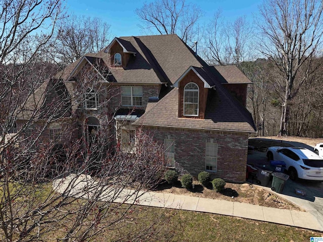 exterior space with brick siding and a shingled roof