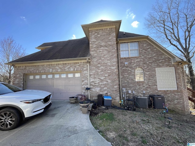 view of property exterior with concrete driveway, brick siding, a garage, and central AC