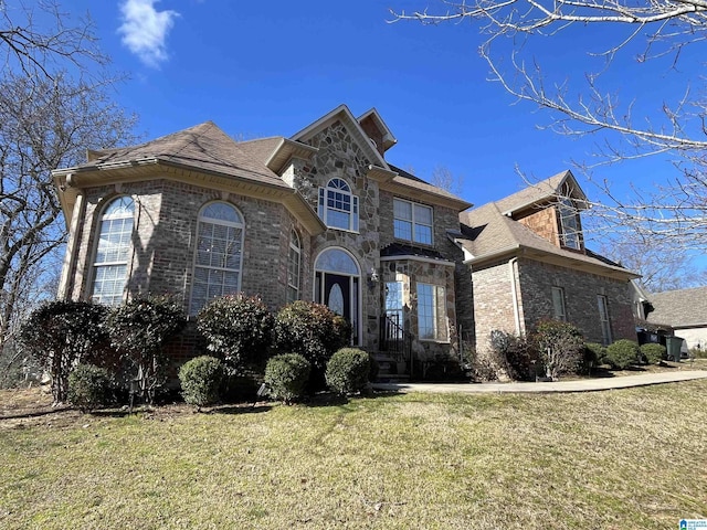 view of front of home featuring brick siding, stone siding, and a front yard