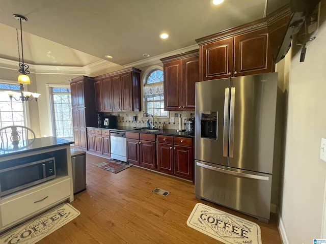 kitchen featuring dark wood-style floors, a sink, stainless steel appliances, dark countertops, and tasteful backsplash