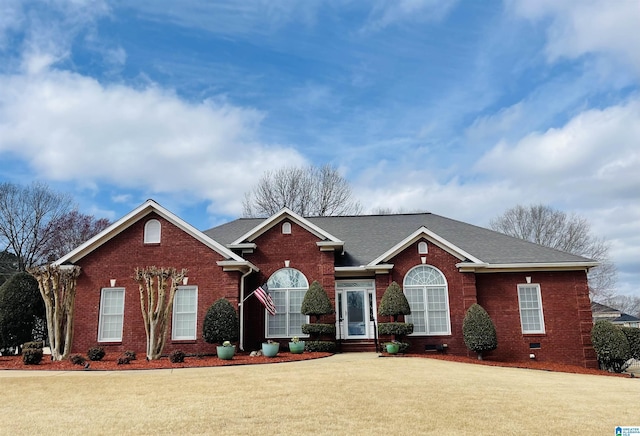 view of front facade with crawl space, a shingled roof, a front lawn, and brick siding