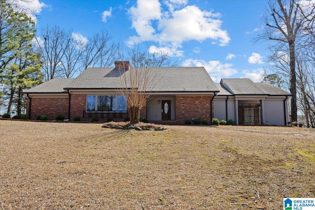 view of front of home with a front yard, brick siding, and a chimney