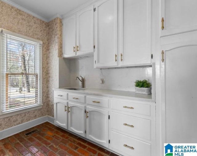 kitchen with brick floor, a wealth of natural light, a sink, and baseboards